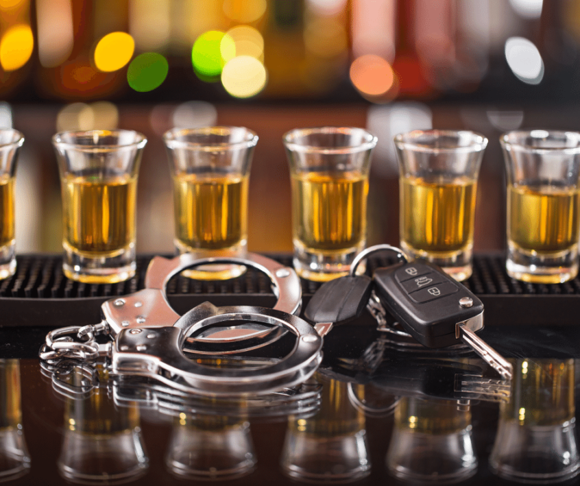 Image of car keys and handcuffs on bar with alcohol behind them